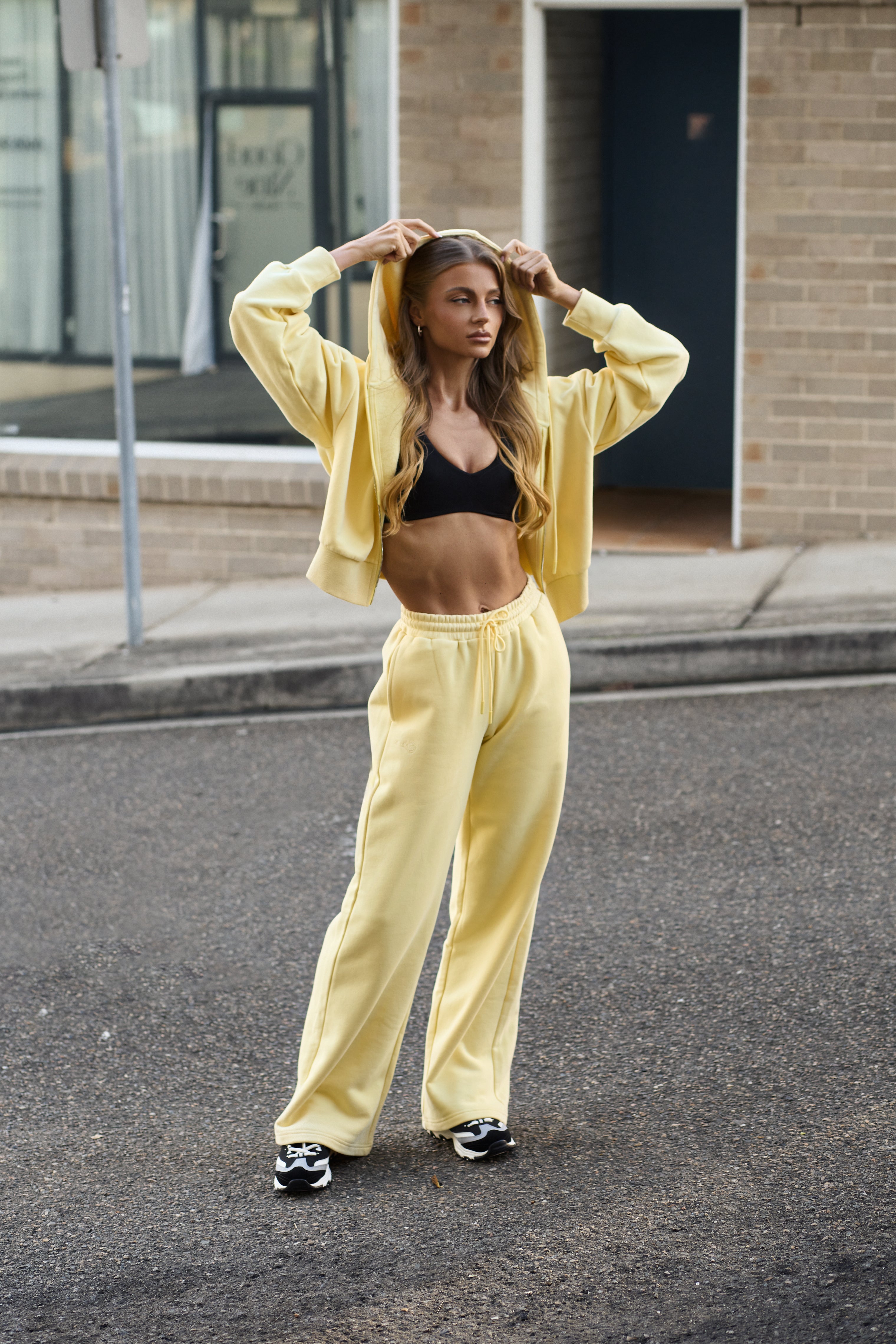 Woman in yellow outfit standing on a street with a building in the background